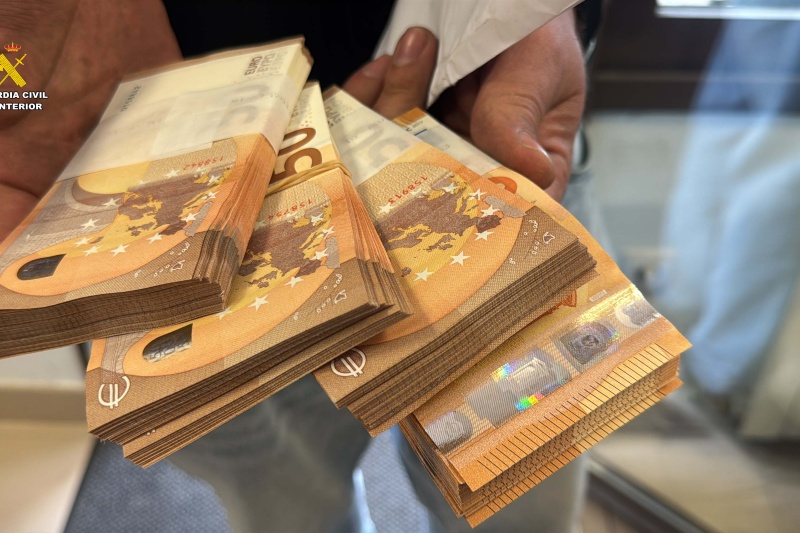 Un guardia civil muestra fajos de billetes intervenidos en la op. portus