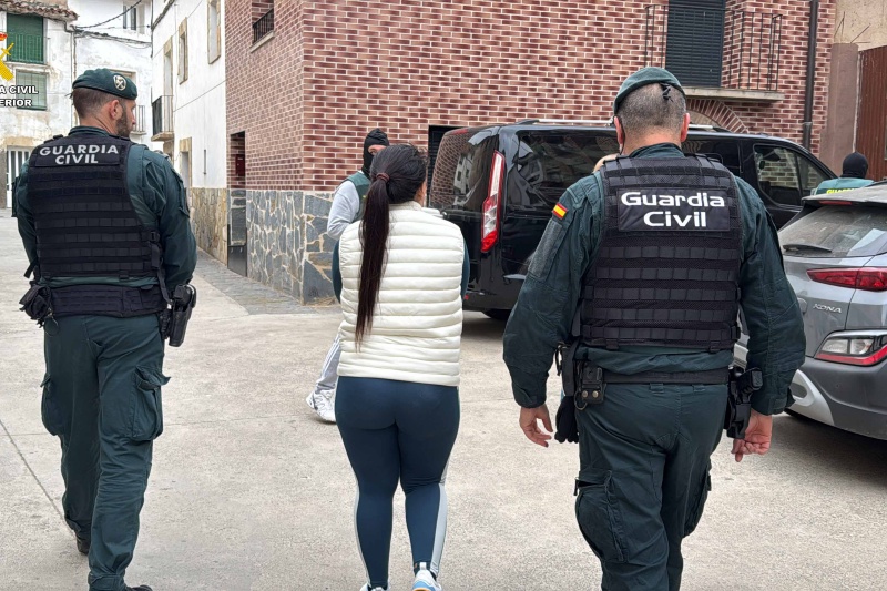 Dos Guardias Civiles custodian a un detenido antes de introducirlo en un coche patrulla