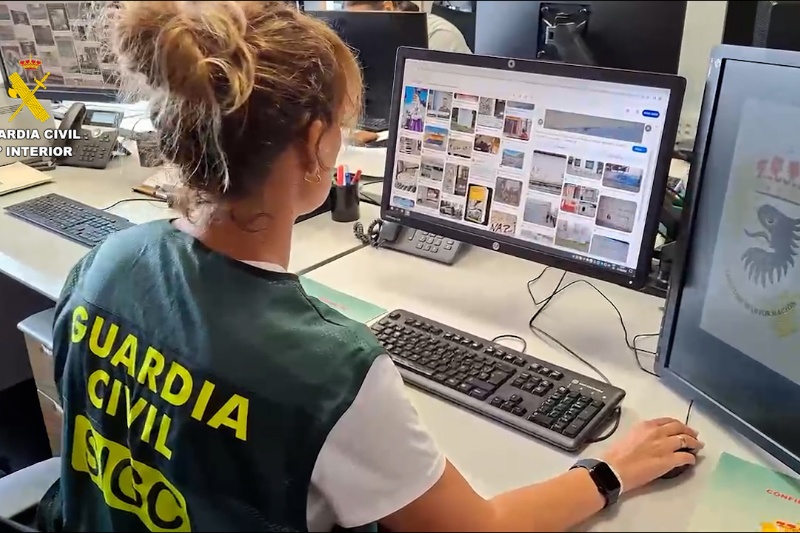 Agente de la guardia civil revisando material fotográfico incautado Agente de la guardia civil revisando material fotográfico incautado