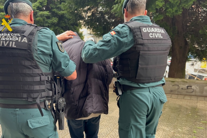 Dos Guardias Civiles custodian a un detenido antes de introducirlo en un coche patrulla