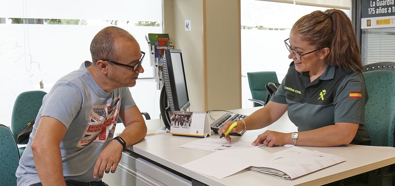 Una guardia civil atiende a un ciudadano en el interior de una oficina de la Guardia Civil